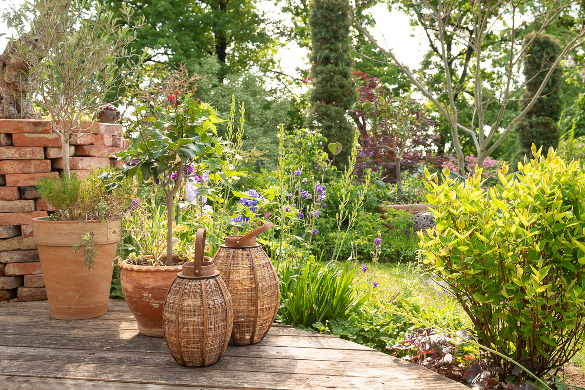 Garten mit Kübelpflanzen und Körben auf der Terrasse