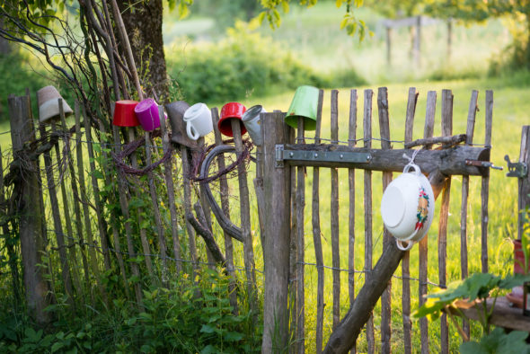 Alter Gartenzaun mit übergestülpten bunten Bechern als Zierde